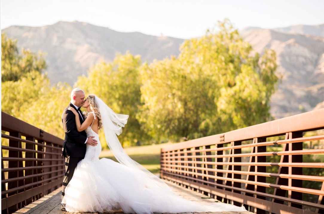 A bride wears a custom Lauren Elaine mermaid backless mermaid wedding gown with cathedral tulle train and veil in Los Angeles, CA at Angeles National Golf Club.