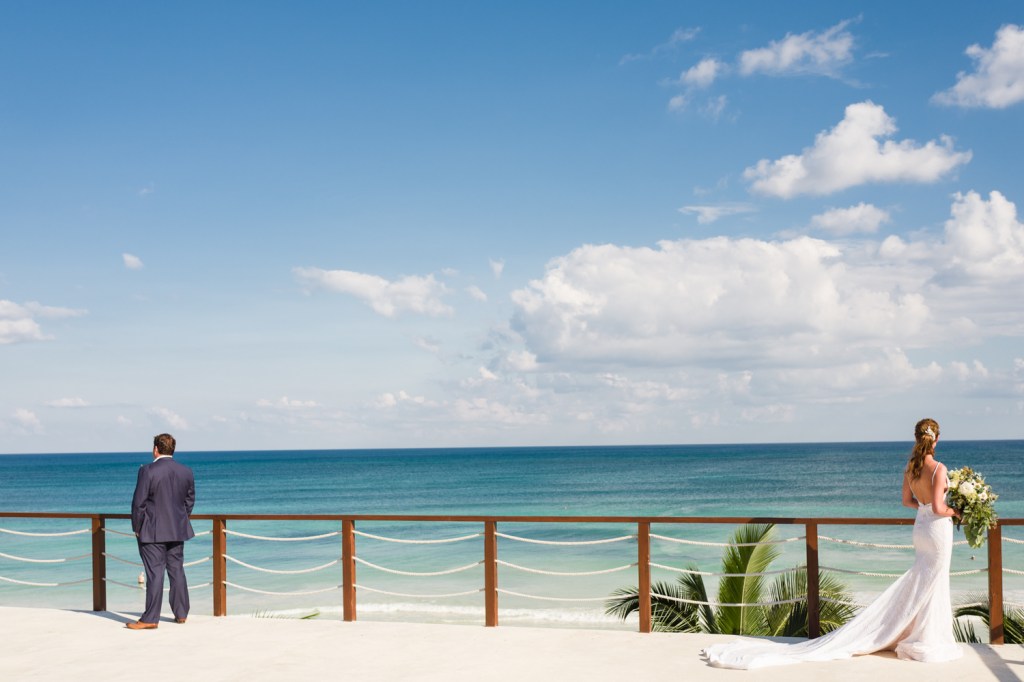 A bride and groom exchange first looks on a beach in Mexico.
