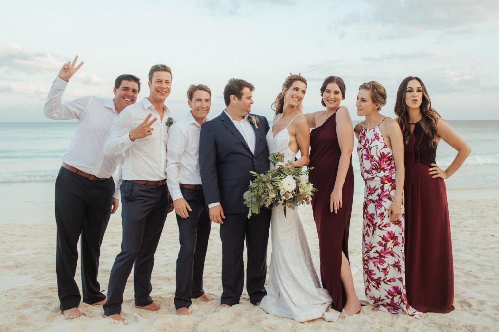 A wedding party celebrates on a beach in Mexico.