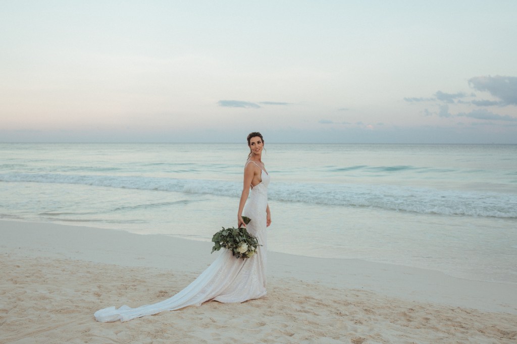 Bride Geniffer poses in her custom Lauren Elaine "Prism" wedding gown on a beach in Mexico with 5ft sequin cathedral train.