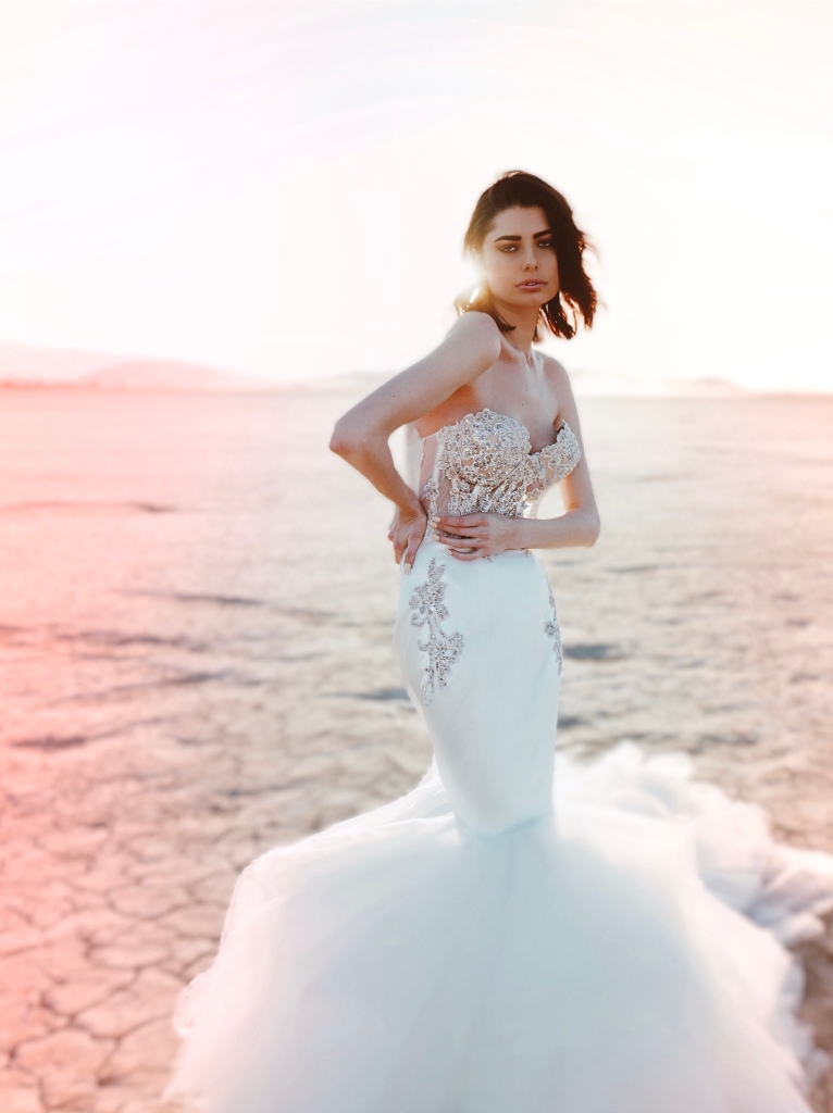 A model wears a satin mermaid wedding dress with beaded lace appliques by Lauren Elaine Los Angeles.