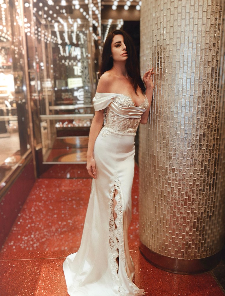A model wears a sexy lace corset and satin trumpet wedding dress with slit on Hollywood Blvd in Los Angeles.