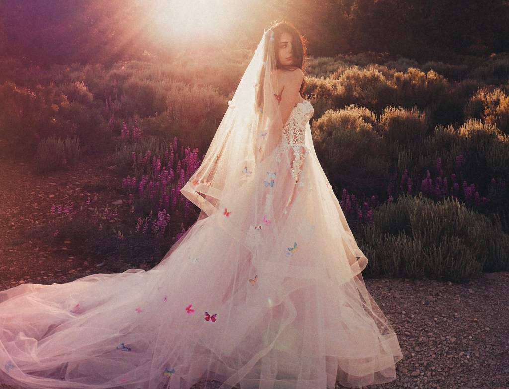 A model wears a rainbow butterfly wedding veil and wedding dress by Lauren Elaine