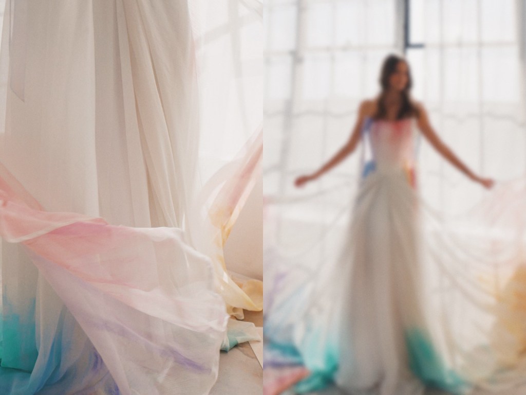 A model poses in a rainbow watercolor wedding dress from the Technicolor Fairytale Collection by Lauren Elaine Los Angeles.