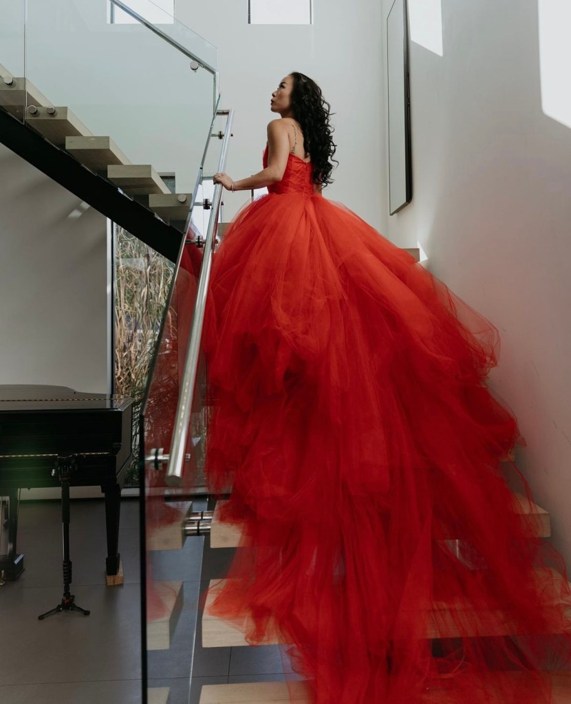 A bride wears a custom red wedding dress by Lauren Elaine on a grand staircase